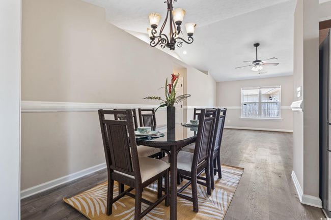 Dining space with vaulted ceiling, wood finished floors, a ceiling fan, and a chandelier | Image 9