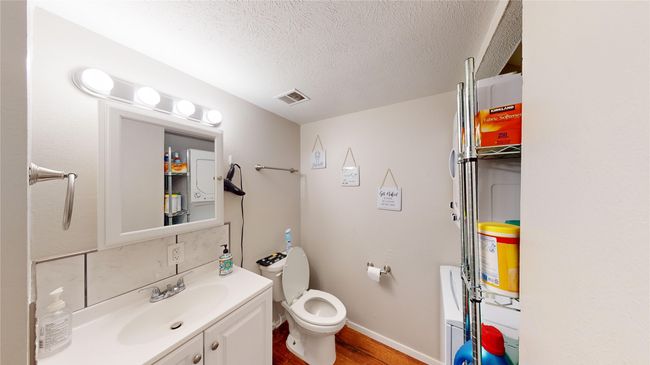 Bathroom with vanity, toilet, a textured ceiling, visible vents, and wood finished floors | Image 4