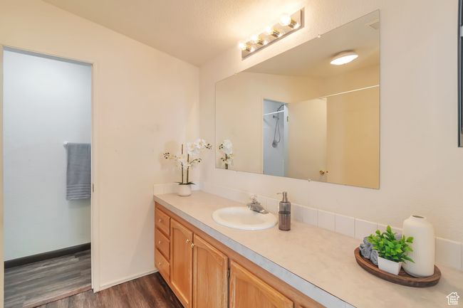 Full bath with wood finished floors, vanity, a shower, and baseboards | Image 13