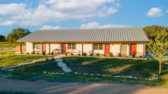 View of front of property with board and batten siding, metal roof, and a front yard | Image 28