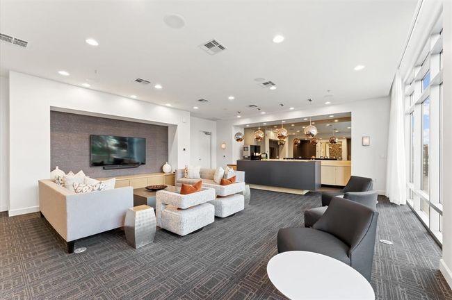 Spacious lounge area with ample seating, a large TV, and a stylish bar are part of the amenities. | Image 24