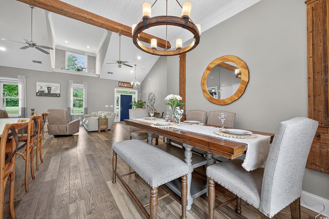 Dining area with a ceiling fan, a chandelier, beamed ceiling, high vaulted ceiling, and wood finished floors | Image 13