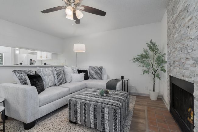 Living area with a ceiling fan, wood finished floors, and a fireplace | Image 11