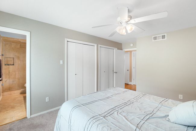 Bedroom with two closets, baseboards, connected bathroom, ceiling fan, and light colored carpet | Image 10