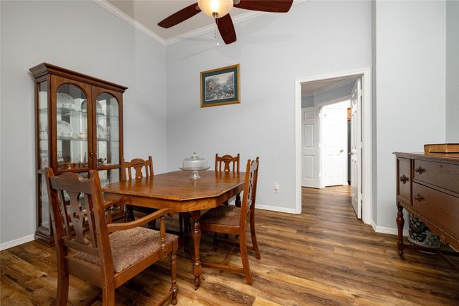 Dining area featuring wood finished floors, crown molding, baseboards, and ceiling fan | Image 7