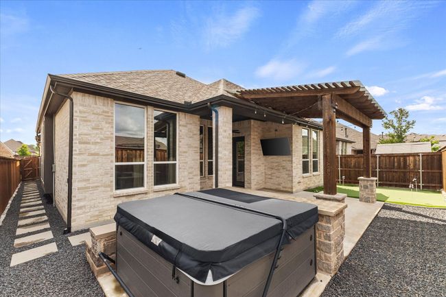 Rear view of property with a hot tub, a putting green, a patio area, a fenced backyard, and roof with shingles | Image 33