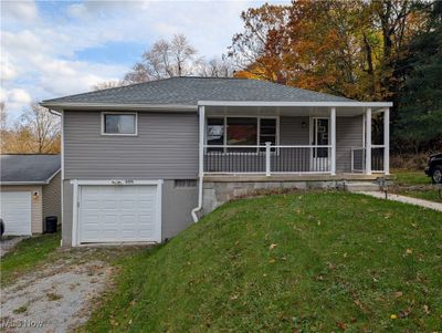 View of front of property with a porch, a front yard, and a garage | Image 1