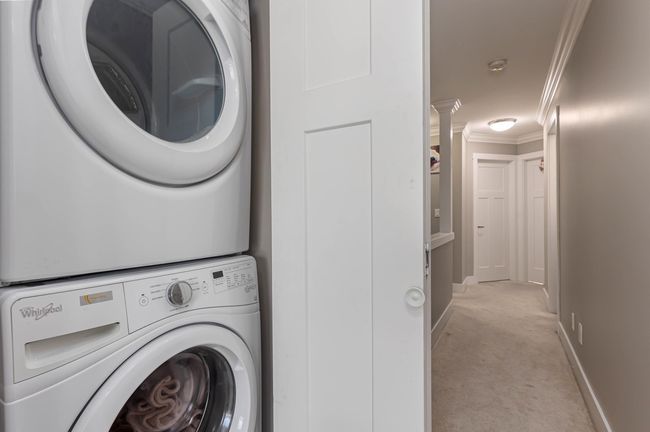 Laundry room with stacked washer / drying machine, crown molding, light carpet, and baseboards | Image 21