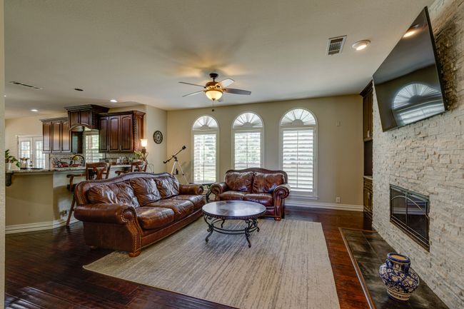 Living room featuring a ceiling fan, dark wood-style flooring, a fireplace, and recessed lighting | Image 8