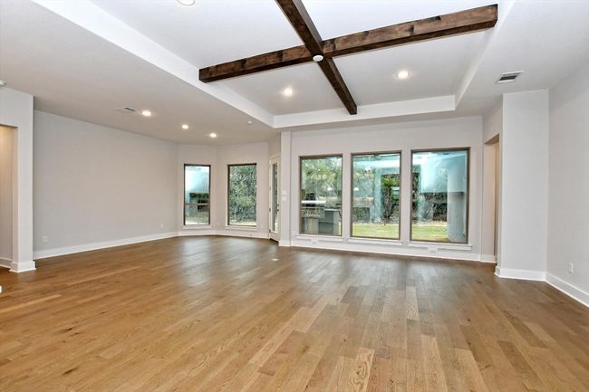 Unfurnished living room with light wood-type flooring, recessed lighting, baseboards, beamed ceiling, and visible vents | Image 8
