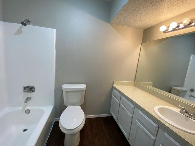 Full bathroom featuring bathtub / shower combination, toilet, a textured ceiling, vanity, and hardwood / wood-style flooring | Image 6