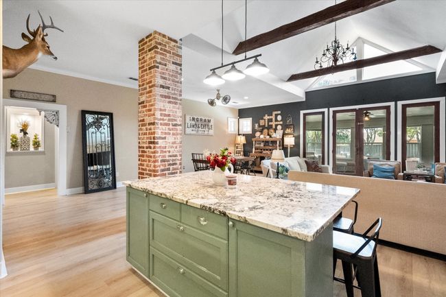 Kitchen featuring green cabinets, light wood finished floors, beam ceiling, a chandelier, and ornate columns | Image 7