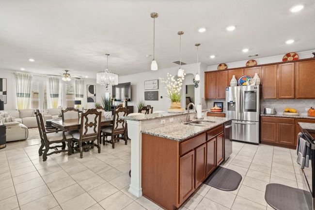 Kitchen with stainless steel appliances, a ceiling fan, backsplash, open floor plan, and light tile patterned floors | Image 8