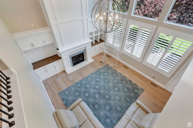 Living room featuring wood finished floors, a chandelier, stairs, a fireplace, and baseboards | Image 27