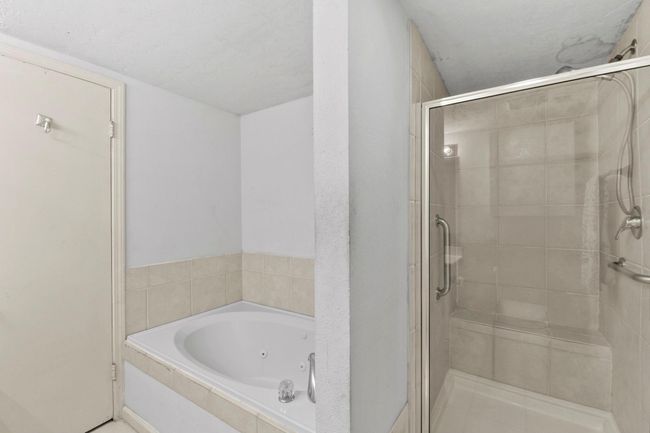 Relax in the luxurious primary bathroom featuring a Jacuzzi-style tub and a walk-in shower. | Image 23