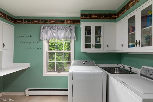 Laundry room with cabinets, washing machine and dryer, sink, baseboard heating, and light tile floors | Image 29