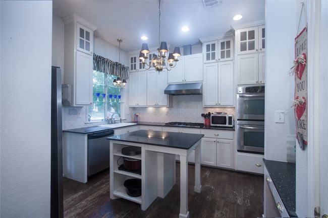 Kitchen featuring appliances with stainless steel finishes, under cabinet range hood, a chandelier, dark wood-style flooring, and recessed lighting | Image 10