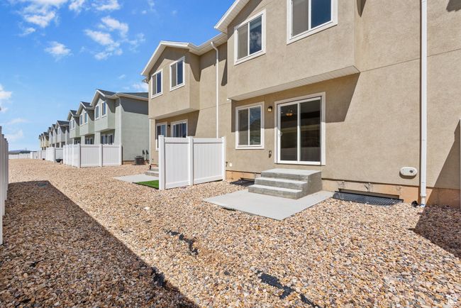 Rear view of townhome featuring stucco siding, a residential view, and a patio | Image 9