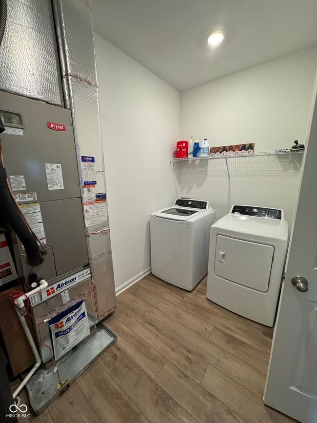 laundry room with heating unit, laundry area, independent washer and dryer, light wood-style floors, and baseboards | Image 16