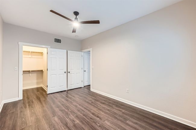 Unfurnished bedroom featuring dark wood-style flooring, a walk in closet, a closet, and a ceiling fan | Image 8