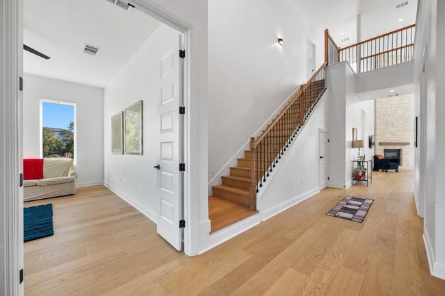 A sleek wood staircase leads to the second level, where three additional bedrooms, a shared bath, a media room, and a game/flex room await | Image 14