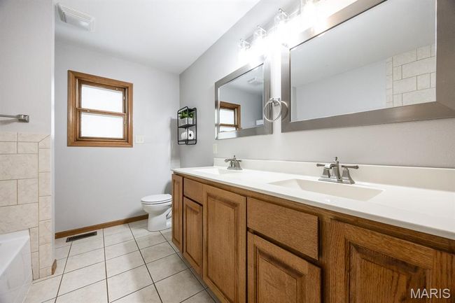 Full bath with double vanity, healthy amount of natural light, toilet, and a tub | Image 23