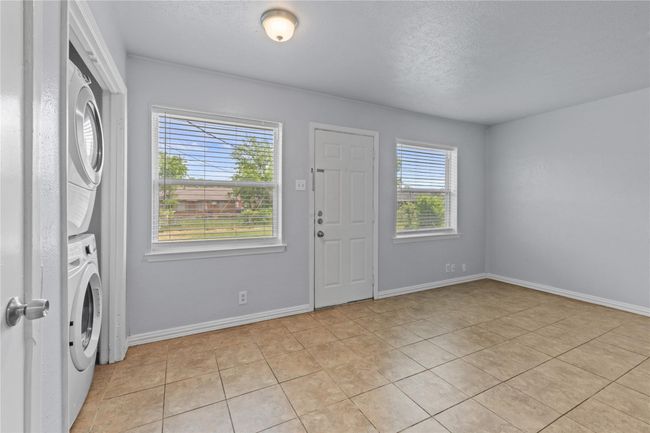 Entrance foyer featuring stacked washing machine and dryer, light tile patterned floors, and a textured ceiling | Image 10