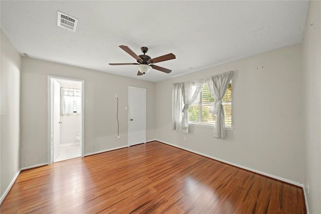 The primary bedroom features wood vinyl floors, a ceiling fan, and a large window with a view of the backyard. It includes an en-suite bathroom and a walk in closed. | Image 17