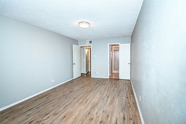 Unfurnished bedroom with light wood-type flooring and a textured ceiling | Image 19