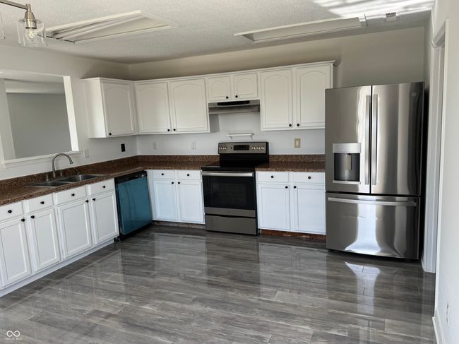 kitchen featuring white cabinets, appliances with stainless steel finishes, under cabinet range hood, and a sink | Image 7