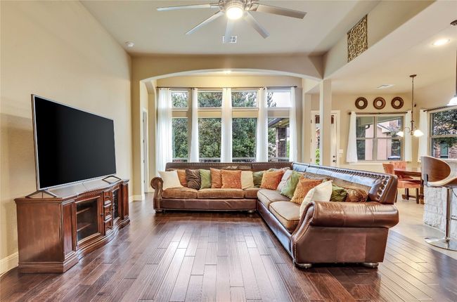 Living room with arched walkways, ceiling fan, and dark wood-style floors | Image 20