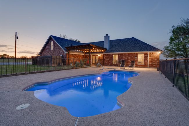 View of swimming pool with fence, a patio area, and a fenced in pool | Image 32