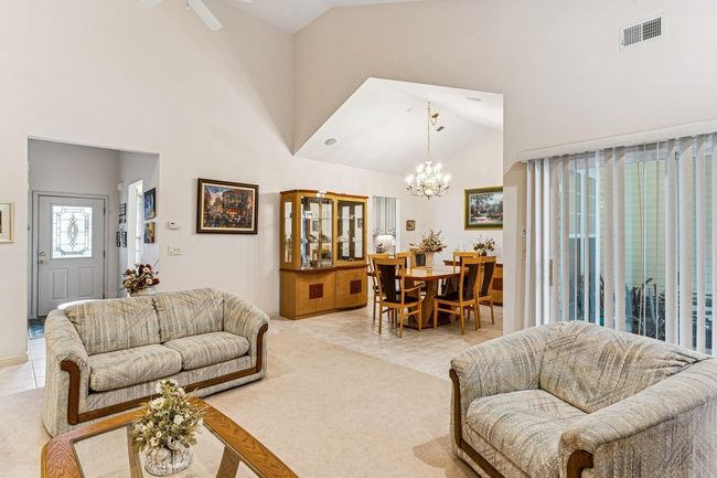 Living area with light tile patterned floors, light carpet, high vaulted ceiling, and visible vents | Image 9