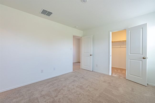 Unfurnished bedroom with light carpet, a spacious closet, baseboards, and a closet | Image 10