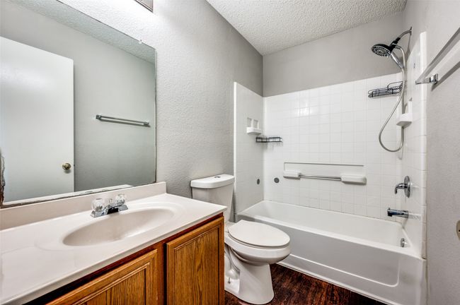 Full bath featuring wood finished floors, toilet, vanity, a textured ceiling, and tub / shower combination | Image 14