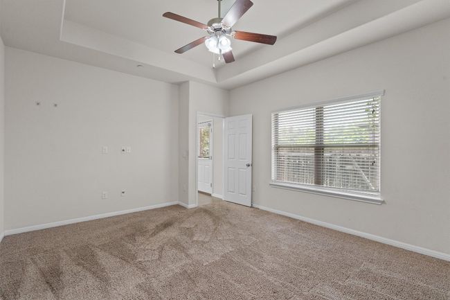 Carpeted spare room featuring a tray ceiling, ceiling fan, and baseboards | Image 16