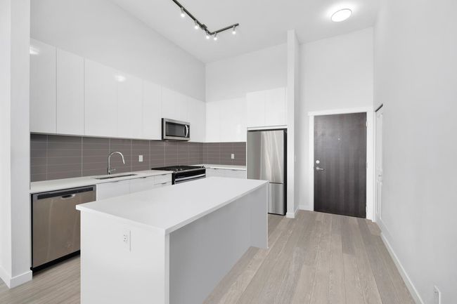 Kitchen featuring white cabinets, stainless steel appliances, a sink, modern cabinets, and light countertops | Image 9