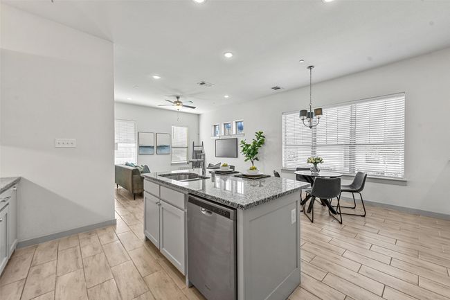 Kitchen featuring ceiling fan with notable chandelier, sink, stainless steel dishwasher, an island with sink, and decorative light fixtures | Image 19