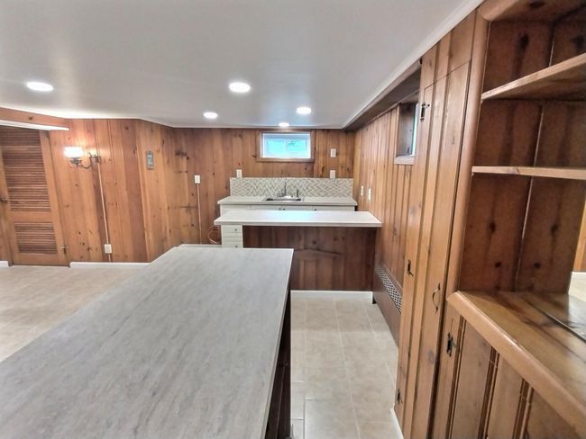 Kitchen with a sink, brown cabinets, light countertops, a peninsula, and wooden walls | Image 27