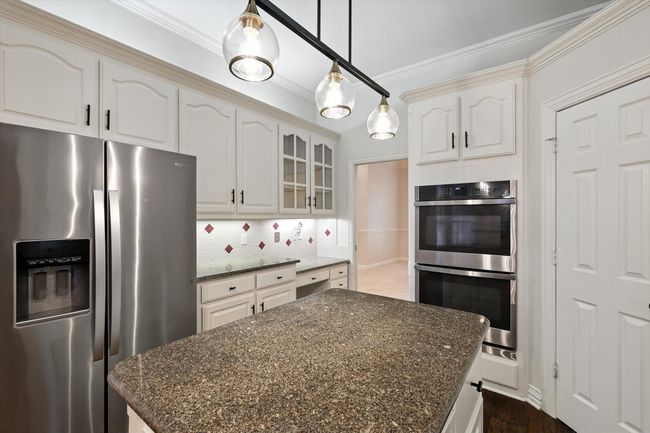Kitchen with stainless steel appliances, crown molding, glass insert cabinets, decorative backsplash, and dark stone counters | Image 7