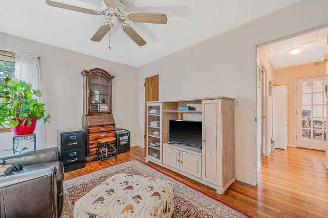Living room with attic access, light wood finished floors, and ceiling fan | Image 13