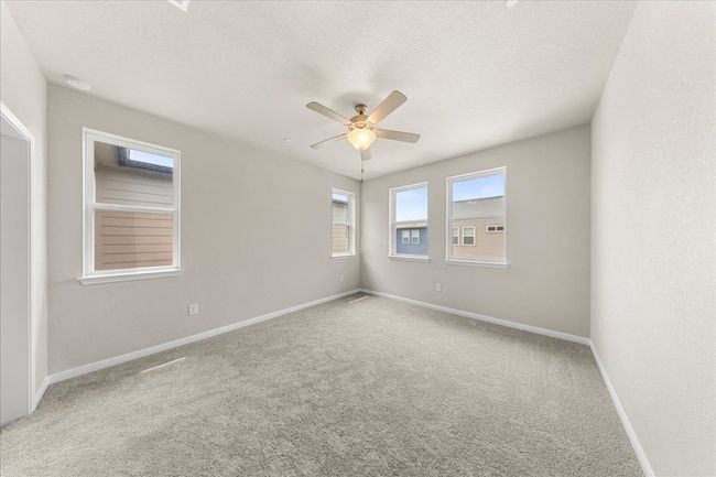 Carpeted empty room featuring ceiling fan, baseboards, and a textured ceiling | Image 25