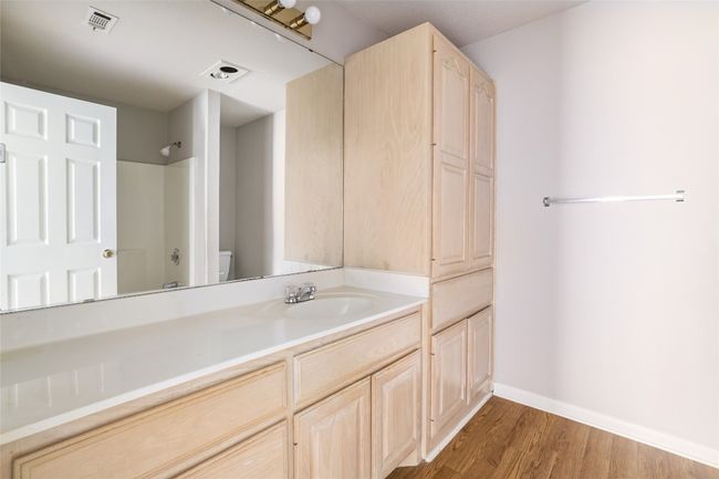 Bathroom with vanity, wood finished floors, toilet, baseboards, and washtub / shower combination | Image 13