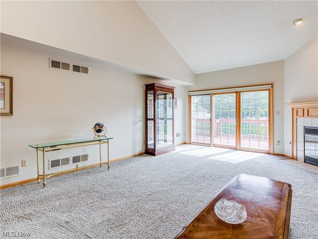Carpeted living room with a high ceiling and lofted ceiling | Image 10