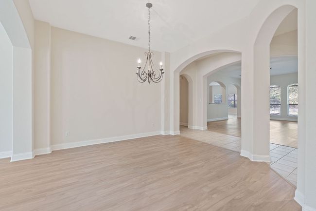 Empty room featuring baseboards, light wood-type flooring, visible vents, and an inviting chandelier | Image 15
