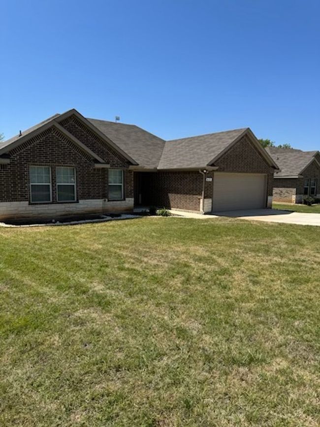 Ranch-style home featuring a garage, a front yard, brick siding, and driveway | Image 21