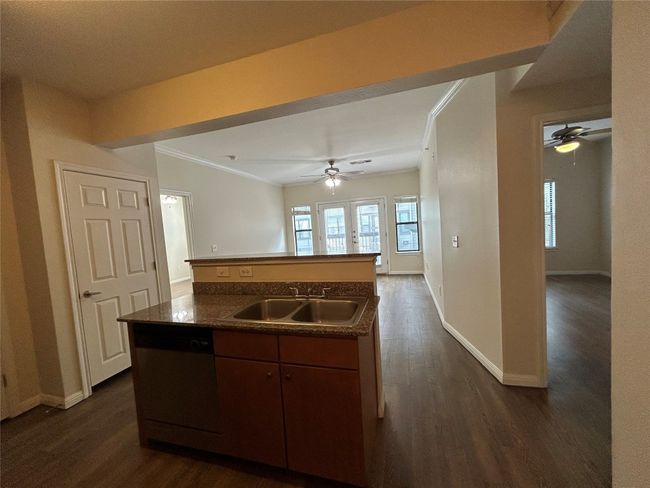 Kitchen featuring a sink, a ceiling fan, ornamental molding, dark countertops, and dark wood finished floors | Image 6