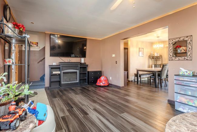 Living area featuring baseboards, crown molding, ceiling fan with notable chandelier, and wood finished floors | Image 4