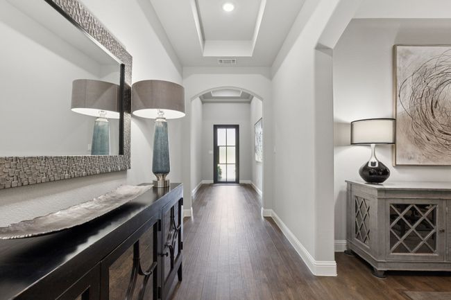 Foyer entrance featuring arched walkways, dark wood-style floors, and a tray ceiling | Image 5