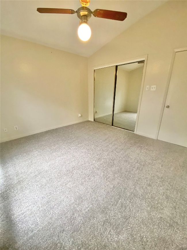 Unfurnished bedroom featuring a ceiling fan, carpet, a closet, and lofted ceiling | Image 21